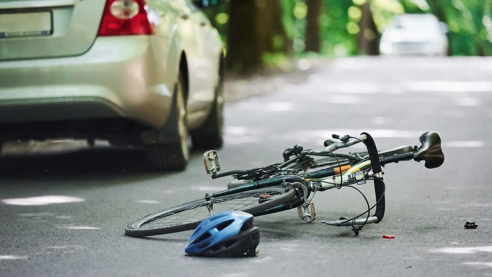 Bei Fahrerflucht drohen hohe Strafen. Ein Fahrrad liegt umgekippt auf der Straße, in der Entfernung ist ein Auto zu sehen.